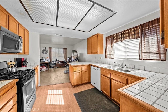 kitchen with appliances with stainless steel finishes, sink, and tile countertops