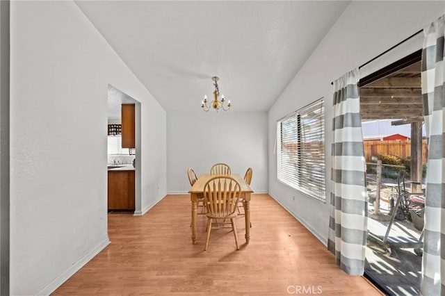 dining space featuring light wood-type flooring, lofted ceiling, and a notable chandelier