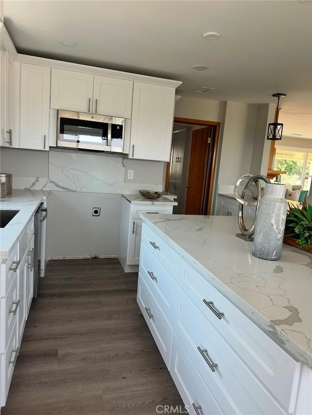 kitchen featuring decorative light fixtures, white cabinetry, stainless steel appliances, tasteful backsplash, and light stone counters