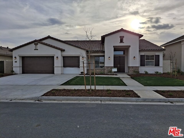 mediterranean / spanish home featuring a lawn and a garage