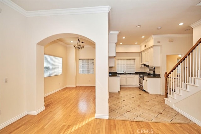 kitchen featuring gas range, sink, light tile patterned floors, and ornamental molding