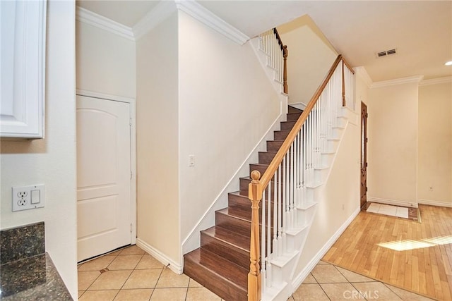 stairway with tile patterned flooring and crown molding