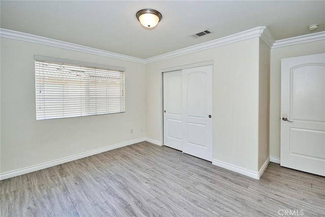 unfurnished bedroom with light wood-type flooring, a closet, and ornamental molding