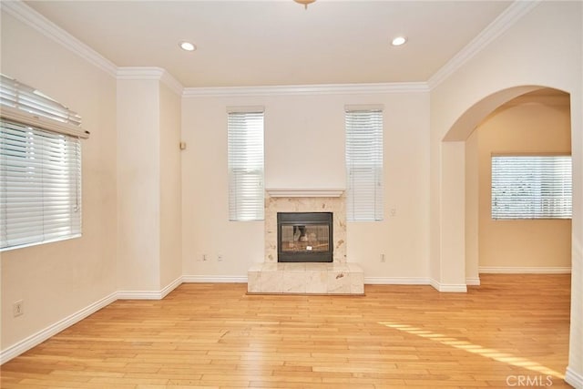 unfurnished living room featuring a fireplace, light hardwood / wood-style floors, plenty of natural light, and crown molding