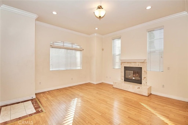 unfurnished living room with crown molding, a premium fireplace, and wood-type flooring