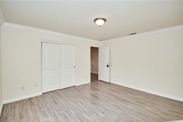 unfurnished bedroom featuring crown molding, a closet, and light hardwood / wood-style floors