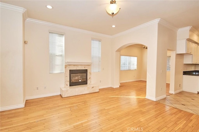 unfurnished living room with light hardwood / wood-style flooring, ornamental molding, and a premium fireplace