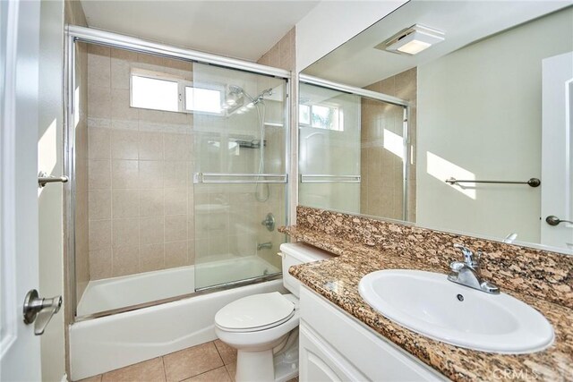 full bathroom with tile patterned flooring, vanity, bath / shower combo with glass door, and toilet