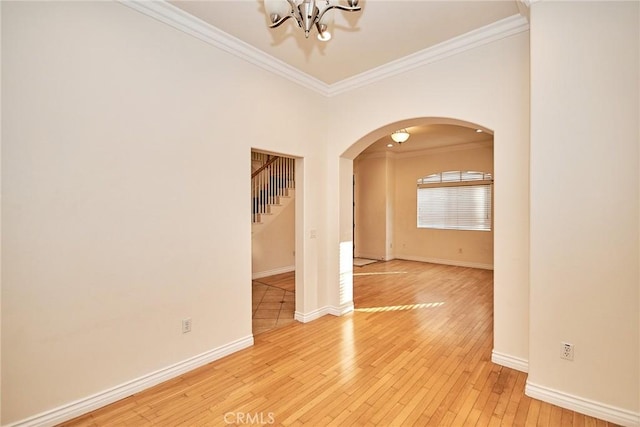 unfurnished room featuring crown molding, a chandelier, and light wood-type flooring