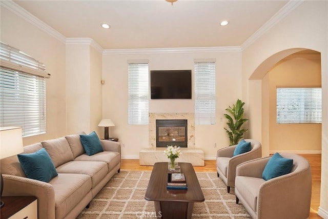 living room with crown molding, a high end fireplace, and light hardwood / wood-style flooring