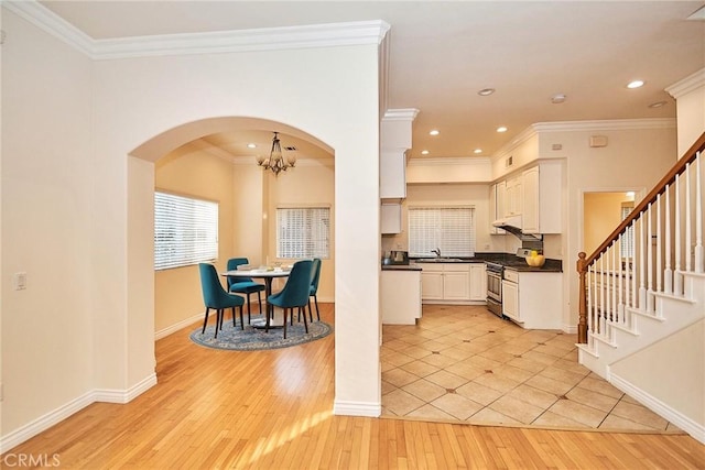 kitchen featuring sink, ornamental molding, light hardwood / wood-style flooring, and stainless steel gas range