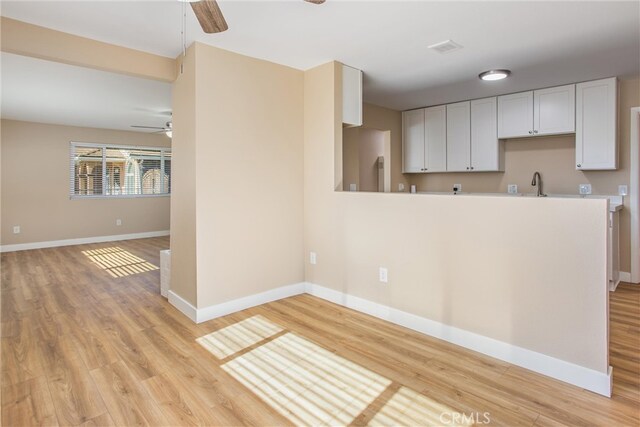 kitchen with ceiling fan, sink, white cabinets, and light wood-type flooring