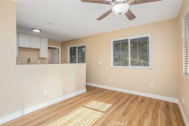 empty room with light hardwood / wood-style floors, sink, and ceiling fan