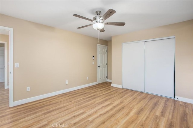 unfurnished bedroom with ceiling fan, light wood-type flooring, and a closet