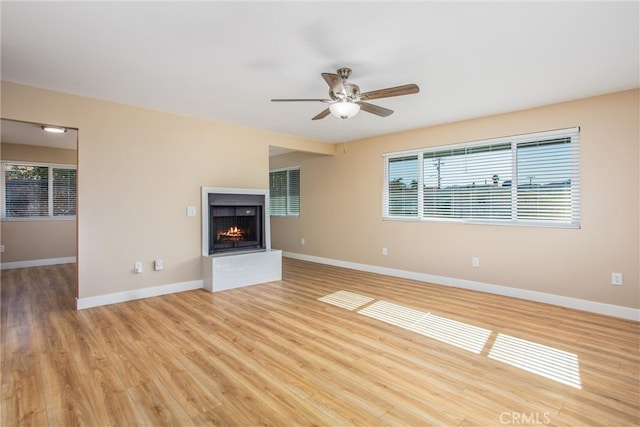 unfurnished living room featuring light hardwood / wood-style floors, ceiling fan, and a fireplace