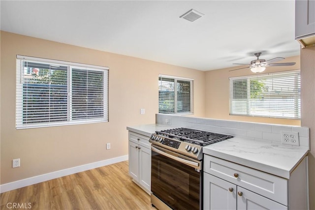 kitchen featuring ceiling fan, light wood-type flooring, stainless steel range with gas cooktop, and light stone counters