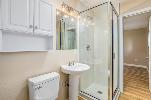 bathroom featuring a shower with shower door, hardwood / wood-style flooring, and toilet