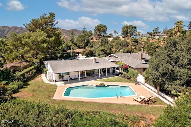 view of pool featuring a patio area, a yard, and a mountain view