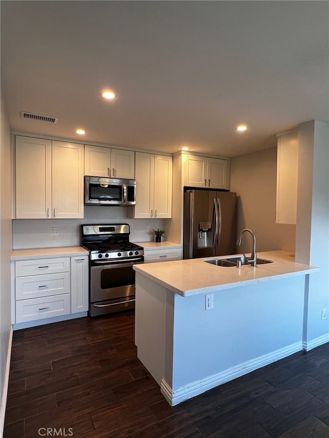 kitchen with sink, white cabinets, dark hardwood / wood-style floors, and stainless steel appliances