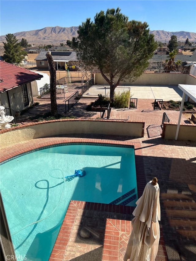 view of swimming pool featuring fence, a mountain view, a fenced in pool, and a patio