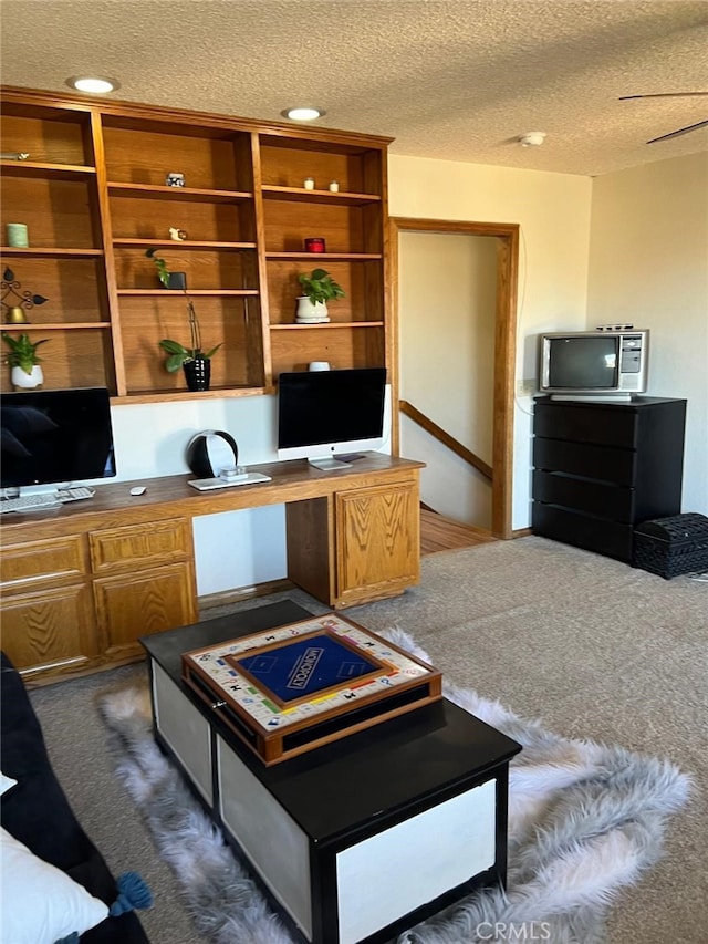 office area with dark colored carpet, built in study area, and a textured ceiling