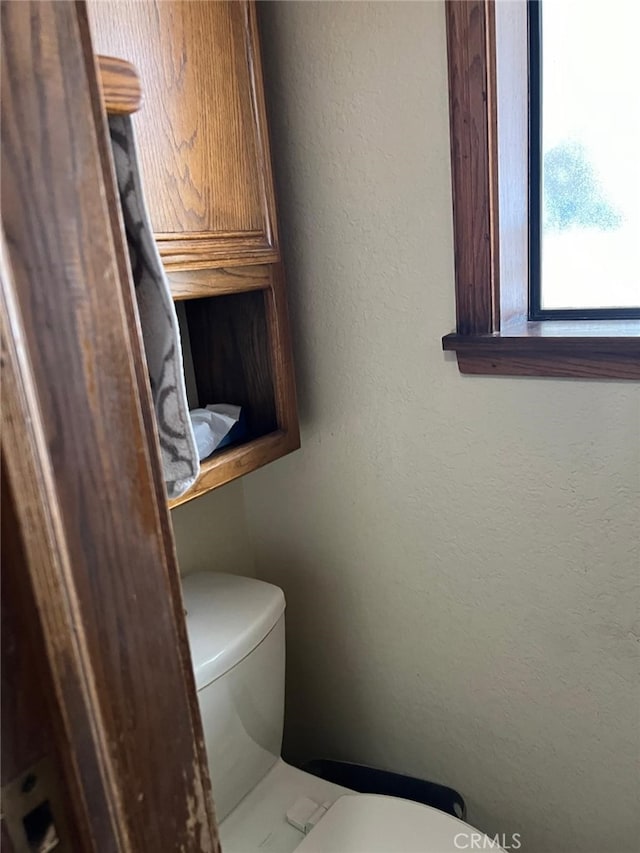 half bathroom featuring toilet and a textured wall