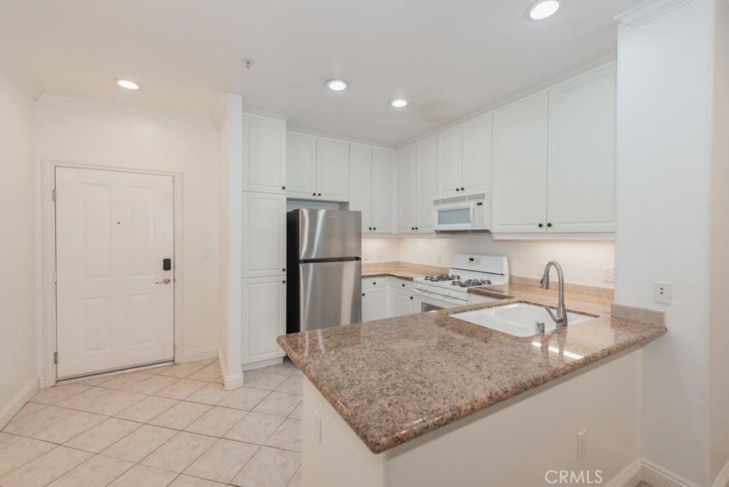 kitchen featuring sink, white cabinetry, kitchen peninsula, white appliances, and light stone countertops