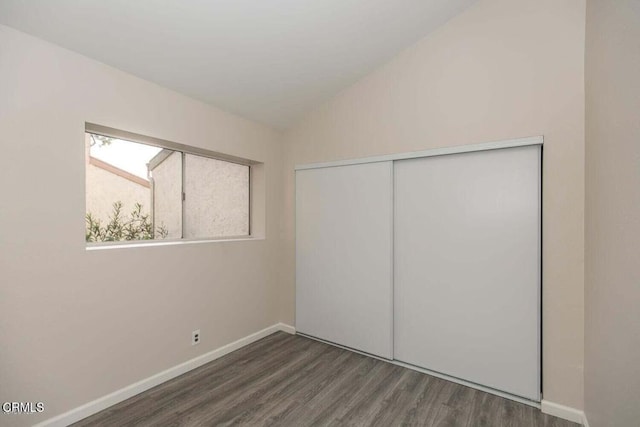 unfurnished bedroom featuring dark wood-type flooring, a closet, and vaulted ceiling