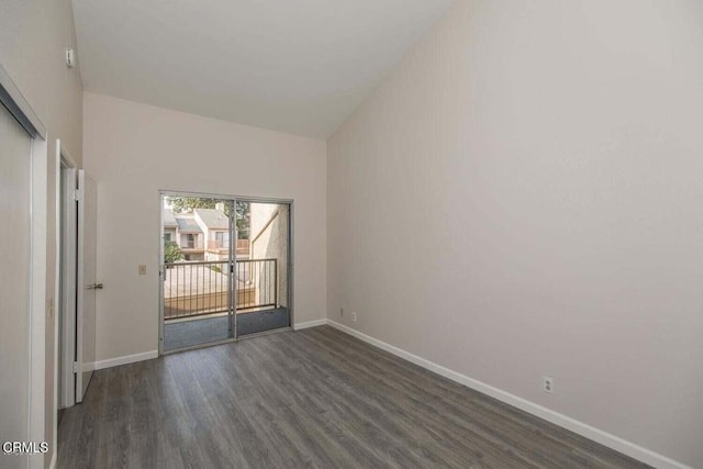 empty room with dark wood-type flooring and a towering ceiling