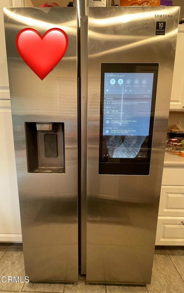 room details featuring stainless steel fridge with ice dispenser and white cabinets