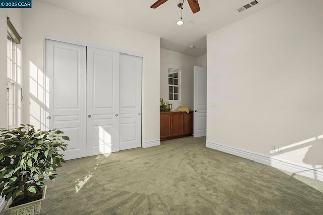 unfurnished bedroom with ceiling fan, a closet, and carpet