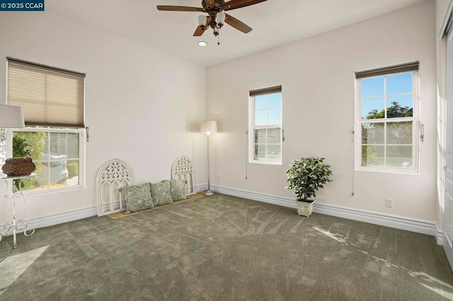 empty room featuring ceiling fan and dark colored carpet