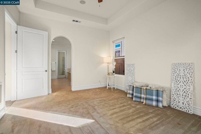 carpeted empty room featuring ceiling fan and a tray ceiling