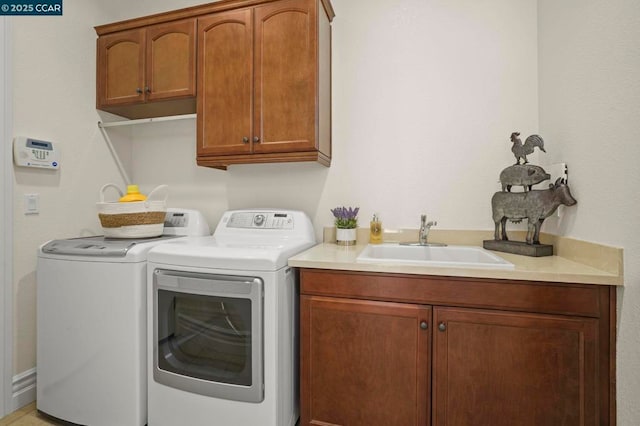 laundry room with washing machine and dryer, cabinets, and sink