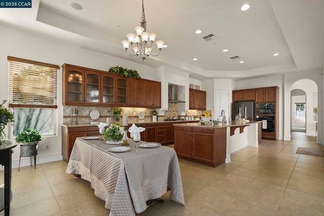 tiled dining space with sink, a tray ceiling, and a notable chandelier