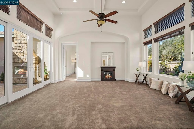 interior space with carpet floors, ceiling fan, a wealth of natural light, and beamed ceiling