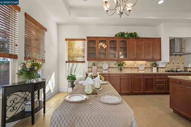 kitchen with hanging light fixtures, wall chimney exhaust hood, a wealth of natural light, and an inviting chandelier