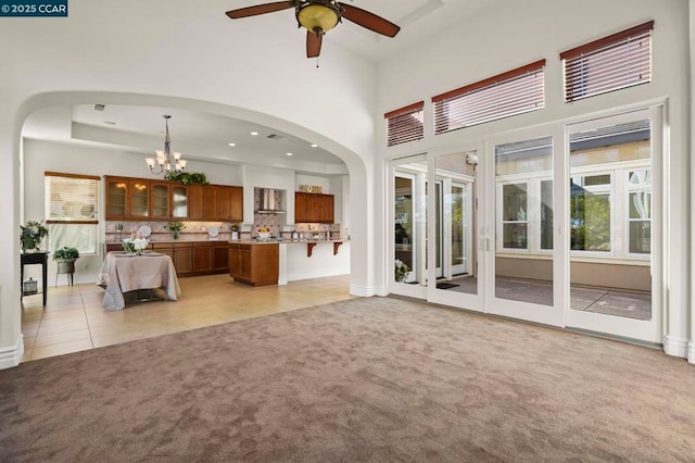 unfurnished living room with ceiling fan with notable chandelier and light colored carpet