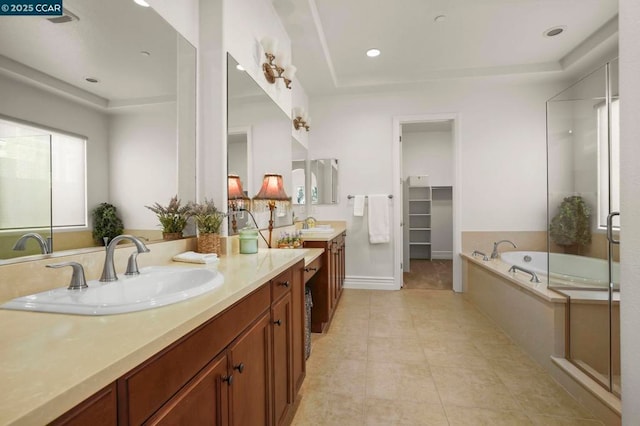 bathroom with a raised ceiling, vanity, tile patterned flooring, and independent shower and bath