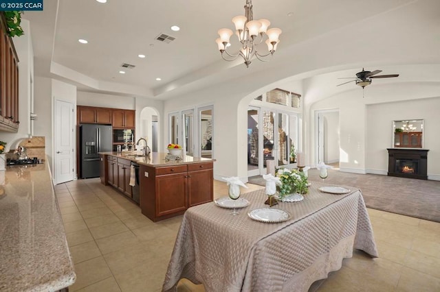 tiled dining space with ceiling fan with notable chandelier and sink