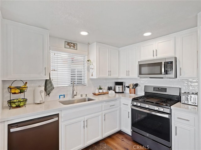 kitchen with sink, stainless steel appliances, dark hardwood / wood-style floors, backsplash, and white cabinets