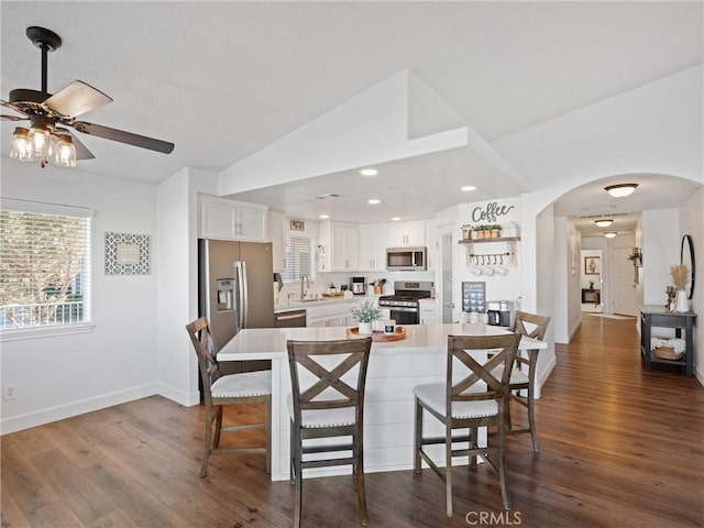 kitchen with dark wood-type flooring, white cabinets, sink, ceiling fan, and stainless steel appliances