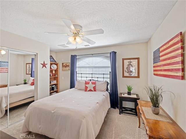 carpeted bedroom featuring ceiling fan and a textured ceiling