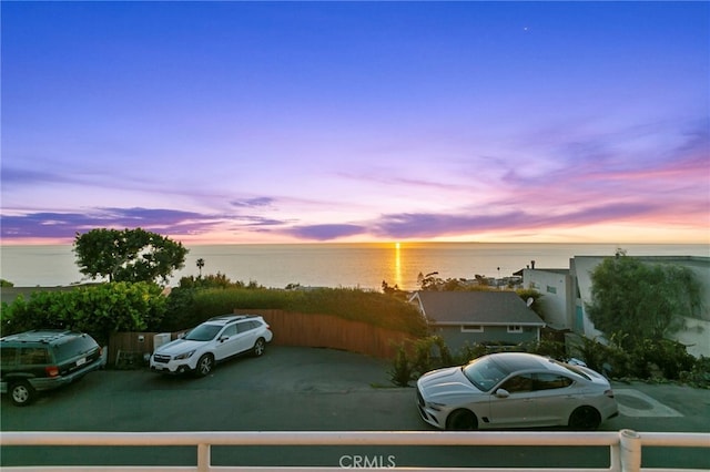 parking at dusk featuring a water view