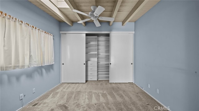 unfurnished bedroom with beamed ceiling, light carpet, wooden ceiling, and a closet