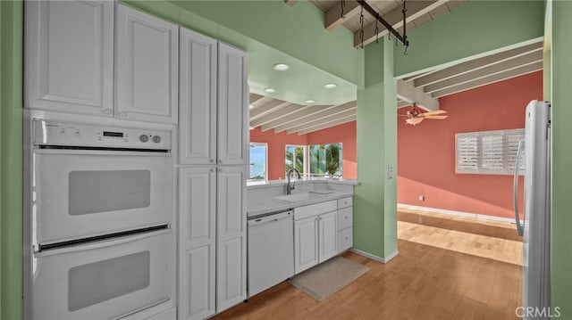 kitchen with white appliances, light hardwood / wood-style flooring, ceiling fan, lofted ceiling with beams, and white cabinets