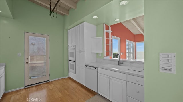 kitchen with white cabinetry, sink, white appliances, and lofted ceiling with beams