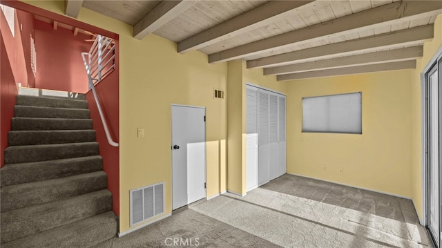 property entrance featuring beamed ceiling, carpet, and wooden ceiling