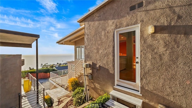 view of exterior entry with a balcony and a water view