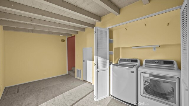 clothes washing area with wood ceiling, light carpet, and washer and dryer